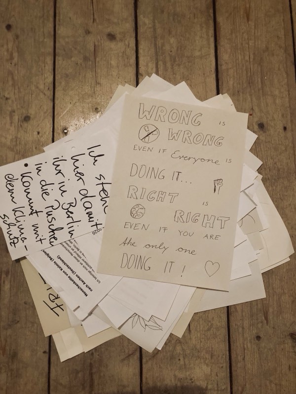 Handgeschriebene Zettel auf Holzdielen, obenauf „Wrong is wrong even if everyone is doing it“